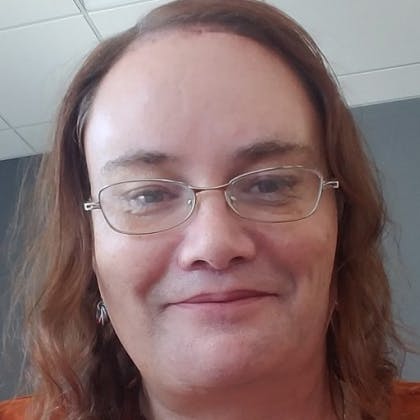 A photo of Diana Fellner, a Coursera Enrollment Counselor. Pictured: A smiling woman with glasses and russet hair