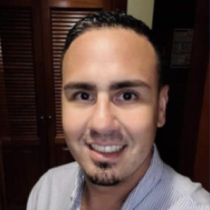 A photo of Marcos Irizary, a Coursera Enrollment Counselor. Pictured: A smiling man with a goatee in a dress shirt