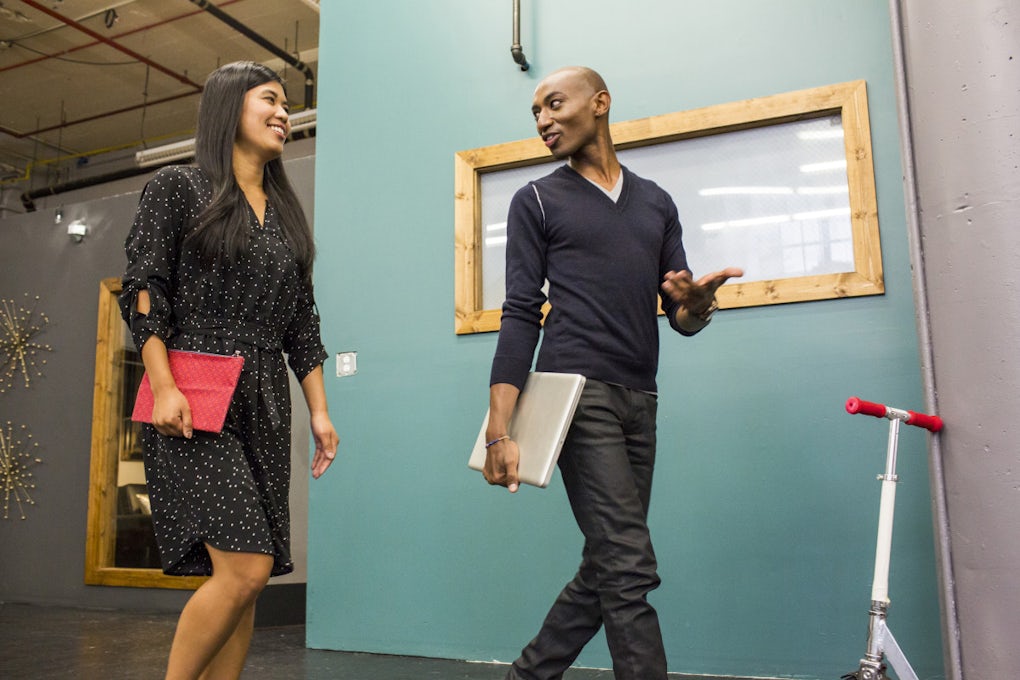 [Featured image] Diverse employees talk in a friendly manner in a turquoise hallway 