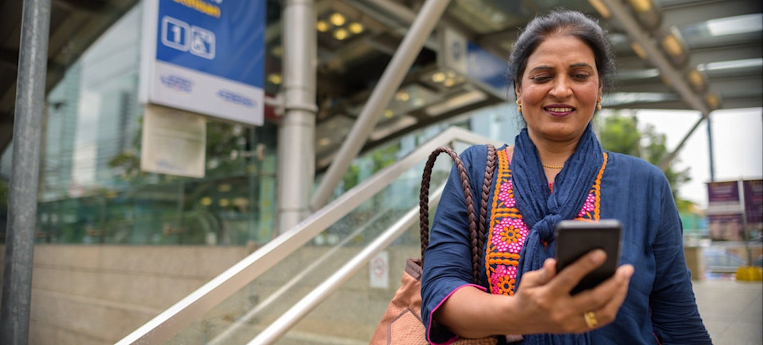 A woman uses a mobile learning platform on her phone outdoors.