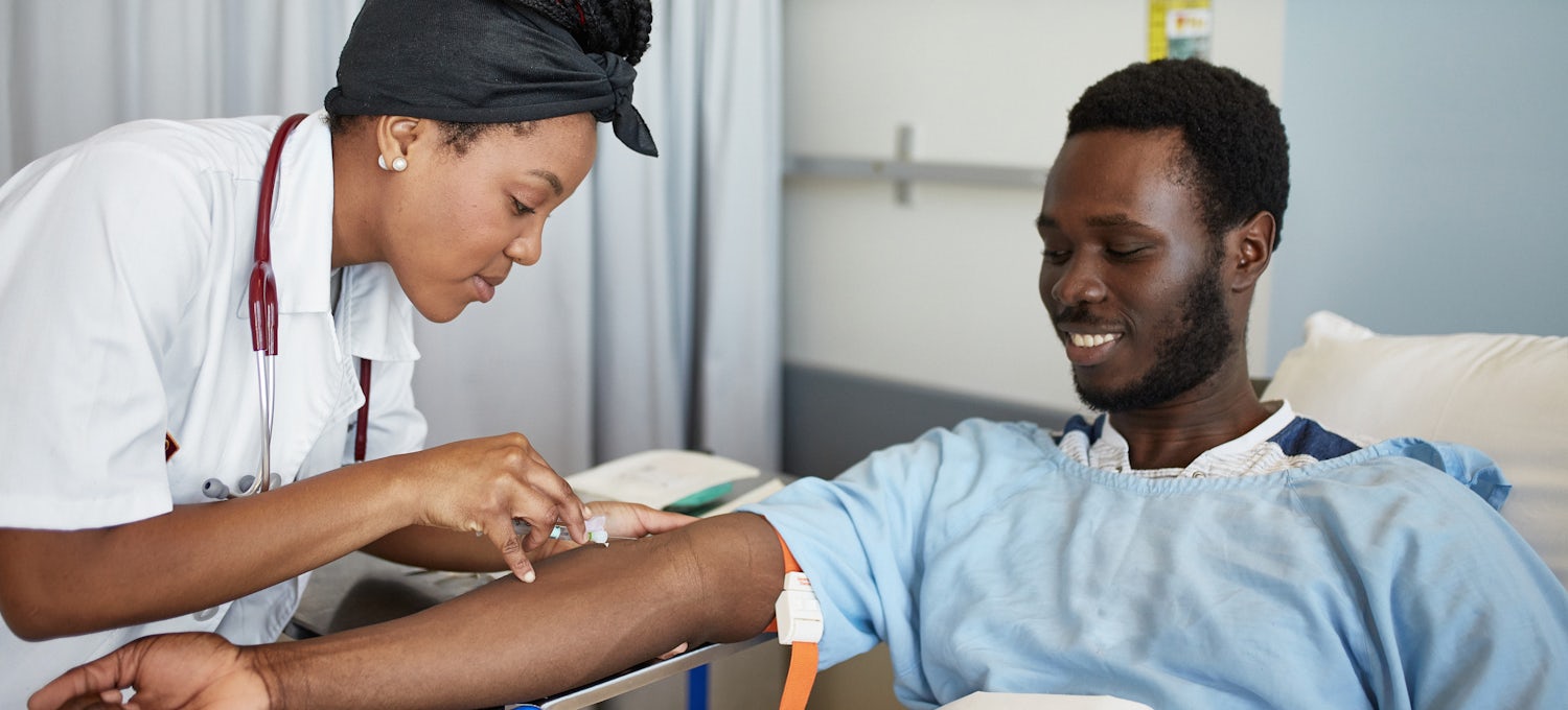 [Featured Image] A phlebotomist cares for a patient in a hospital.
