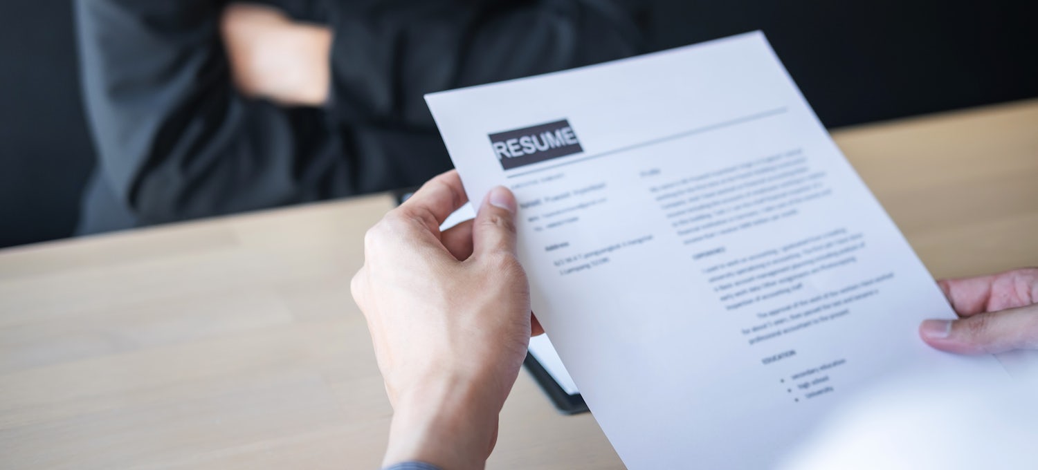 [Featured Images] A photograph of a resume in the hands of a job applicant.