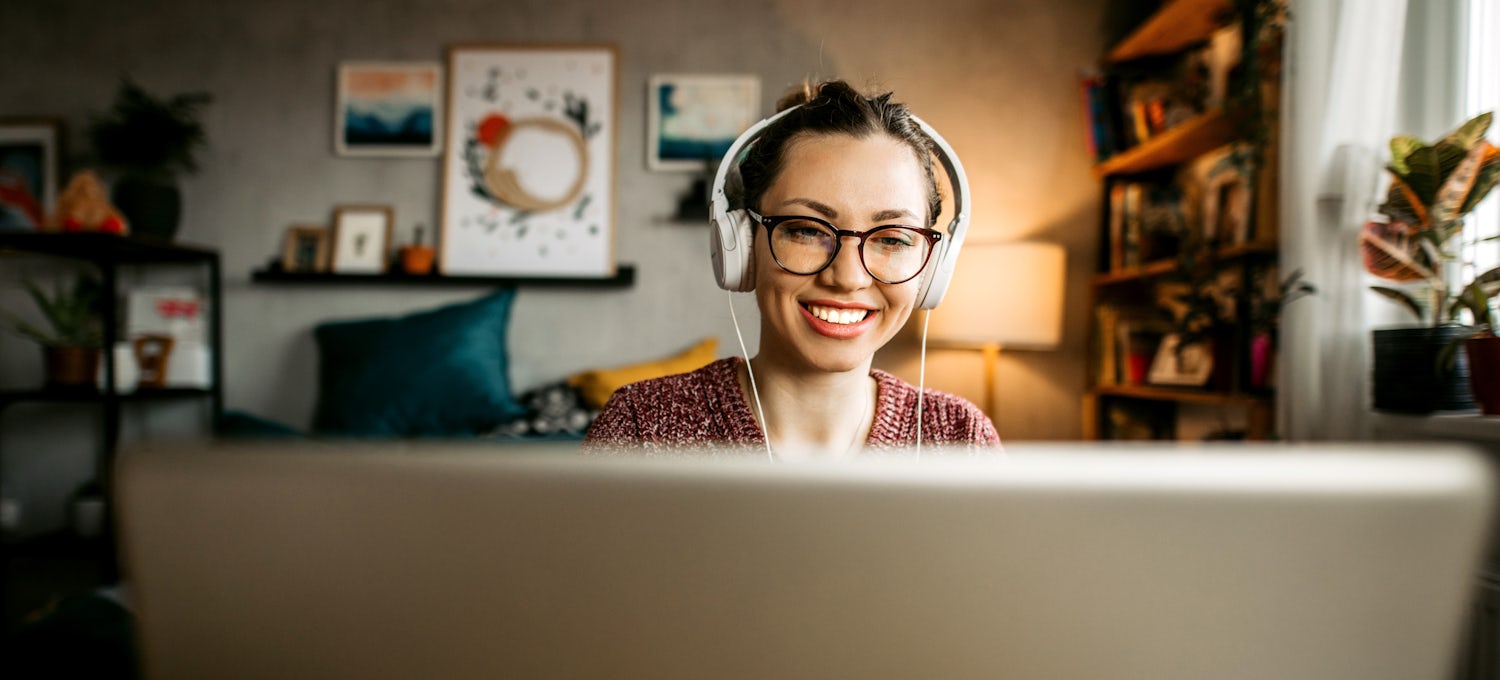 [Imagen destacada] Una persona con camisa morada, auriculares y gafas está sentada delante de un ordenador portátil trabajando en ChatGPT.