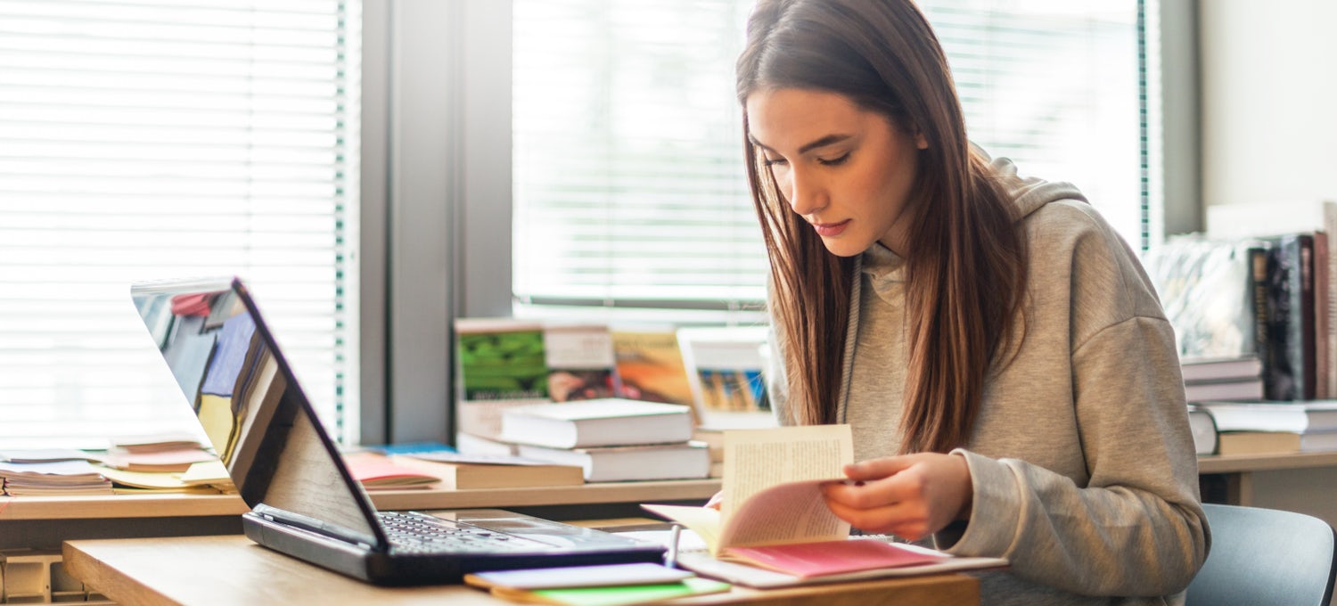 [Featured image] An aspiring project manager looks through several project manager books as she studies for the PMP.