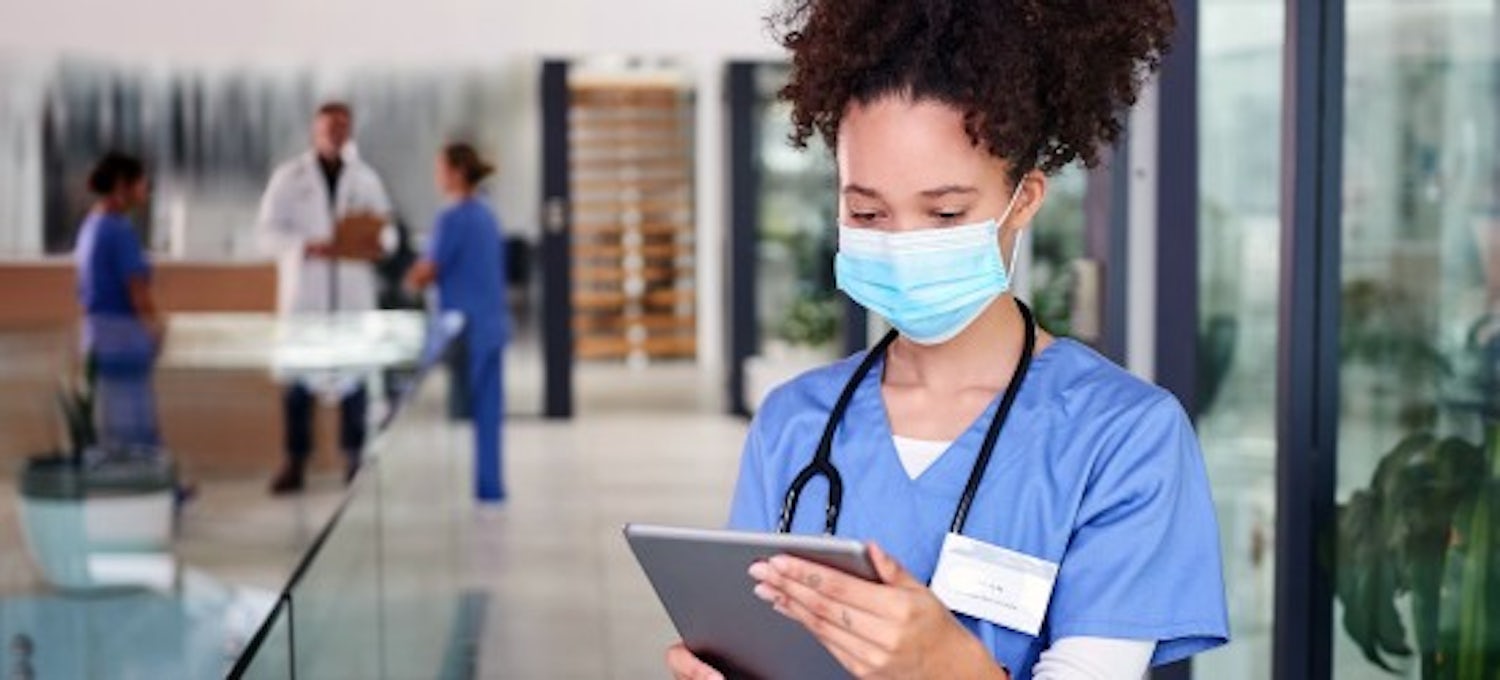 [Featured Image] A nurse practitioner is using a tablet while working in a hospital