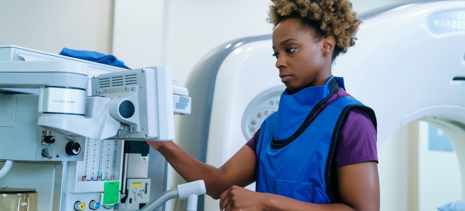 [Featured Image] A woman wearing a protective vest works with radiologic equipment. 