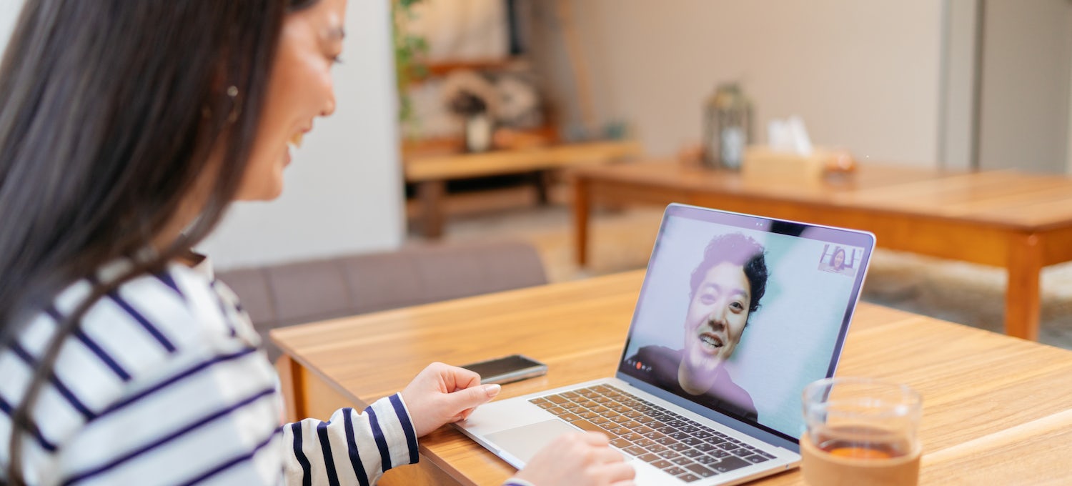 [Imagen destacada] Una representante del servicio de atención al cliente con una camisa de rayas azules y blancas habla con un cliente en su laptop.