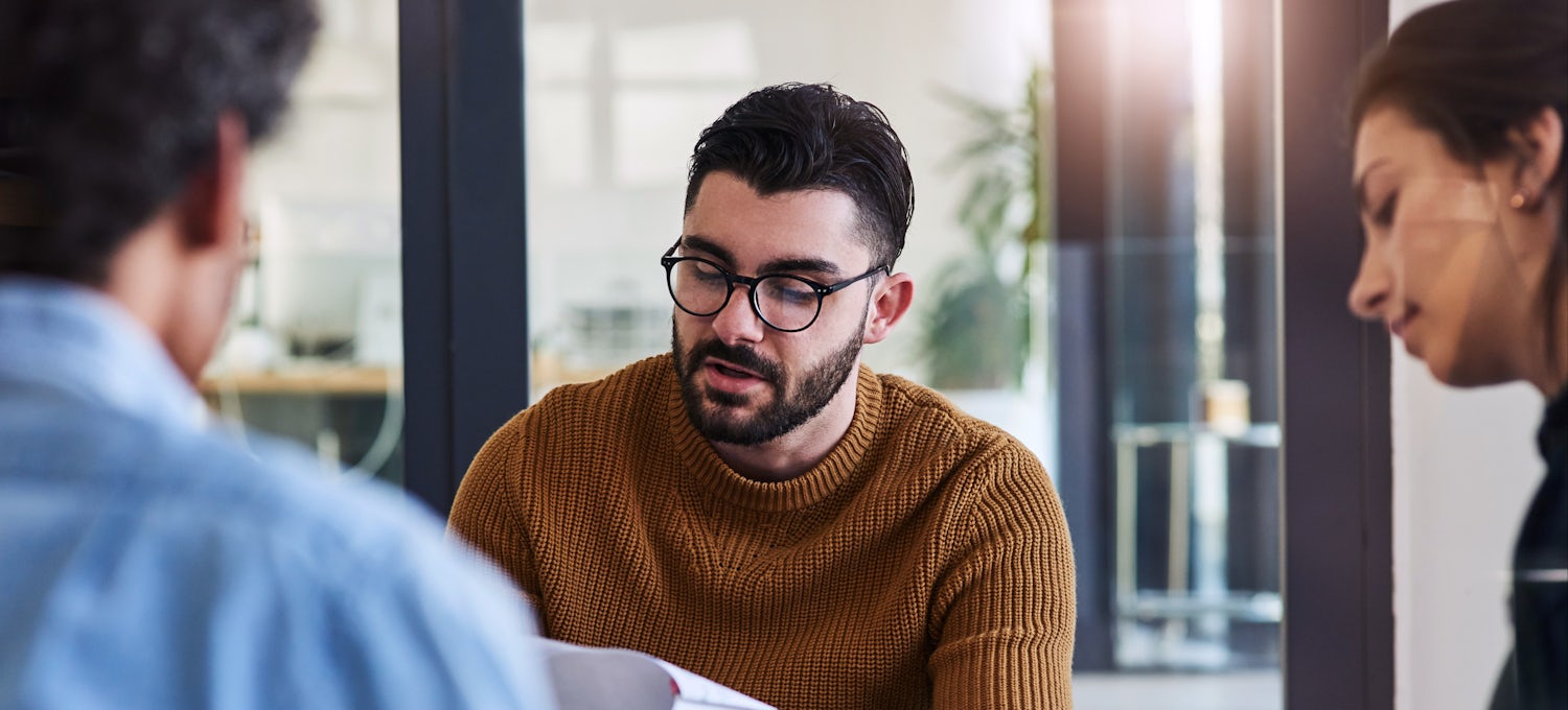 [Featured image] A male, wearing a brown sweater and glasses, is preparing for an interview as a product manager. 