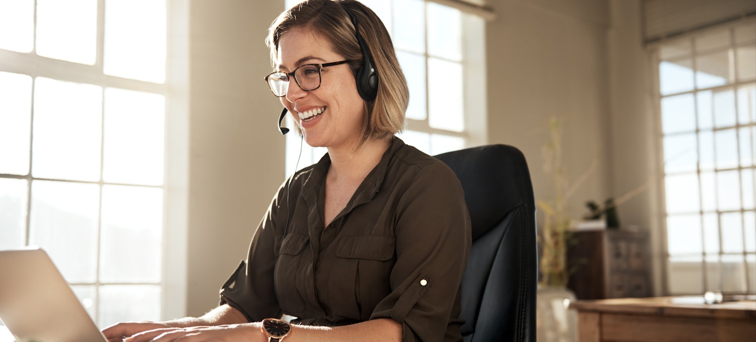 [Featured Image] A UX data analyst wears a headset, sits at a desk in her office, and uses a computer to look at data to determine whether her organization's product is user-friendly. 
