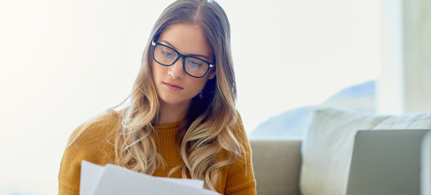 [Featured image] Woman in a yellow sweater with glasses looking at a resume