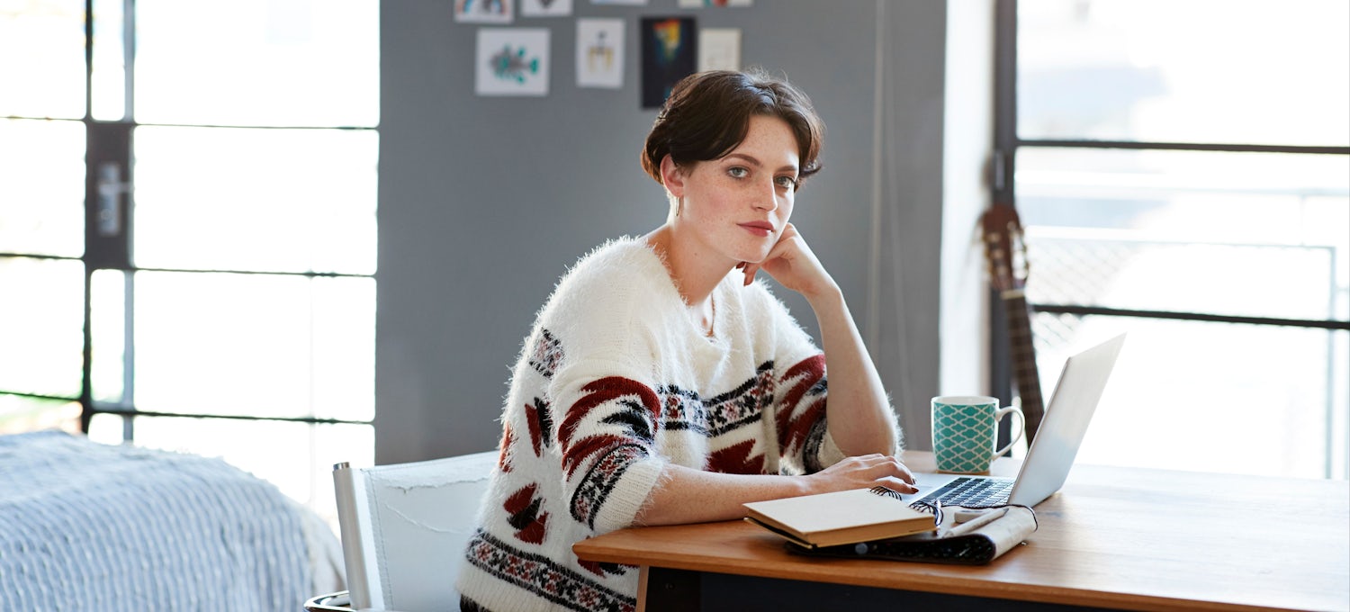 [Imagen destacada] Una mujer trabaja en un escritorio con su laptop y sus libros.