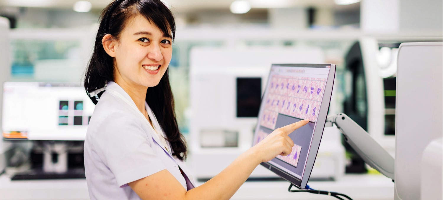 [Featured image] A medical assistant enters patient information on a touch screen monitor in a hospital.