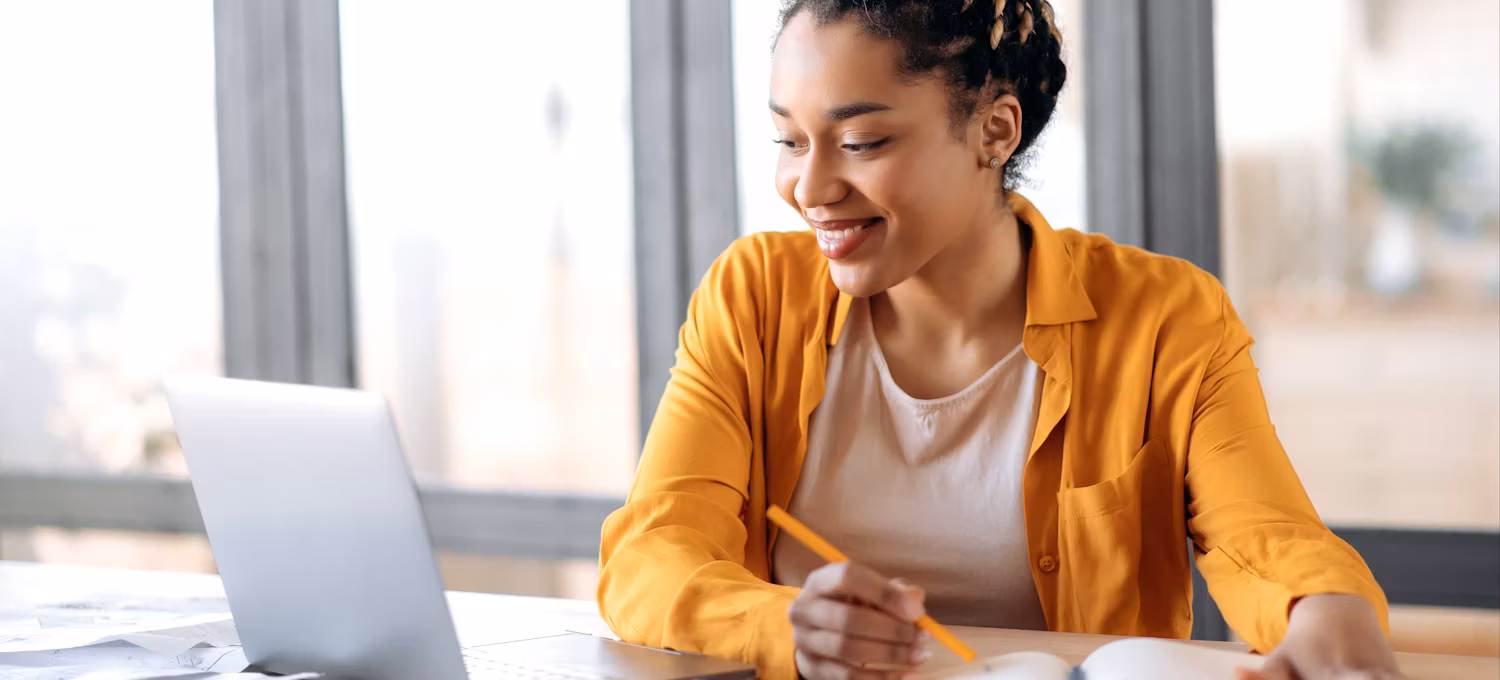 A woman sits at a table with her laptop and researches how fast she can get a bachelor's degree online.