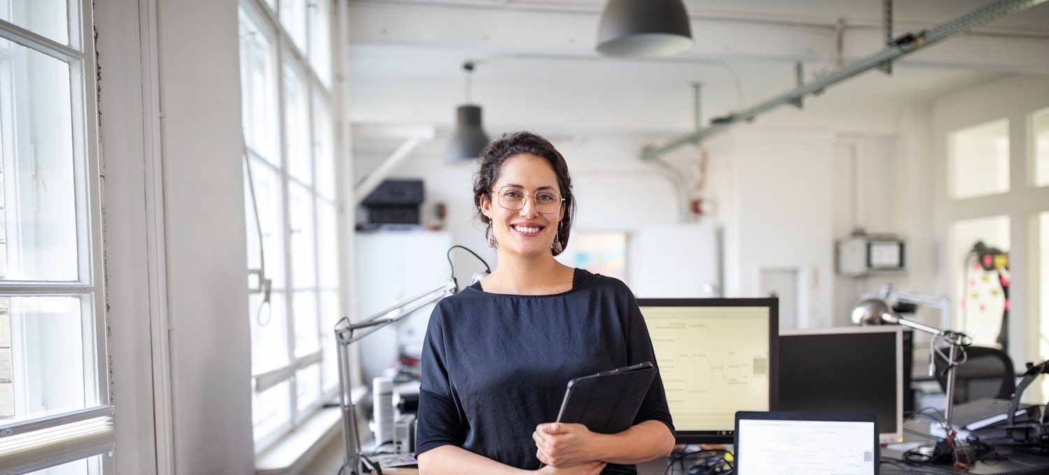 [Featured Image] A woman in a black top stands in an office.