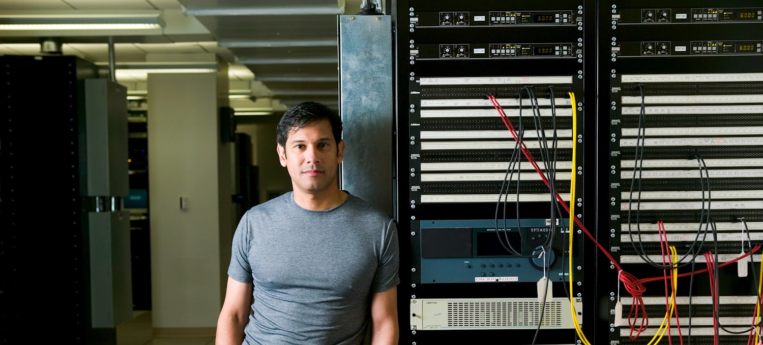 [Featured Image] A computer engineer in a gray T-shirt leans against a server tower.