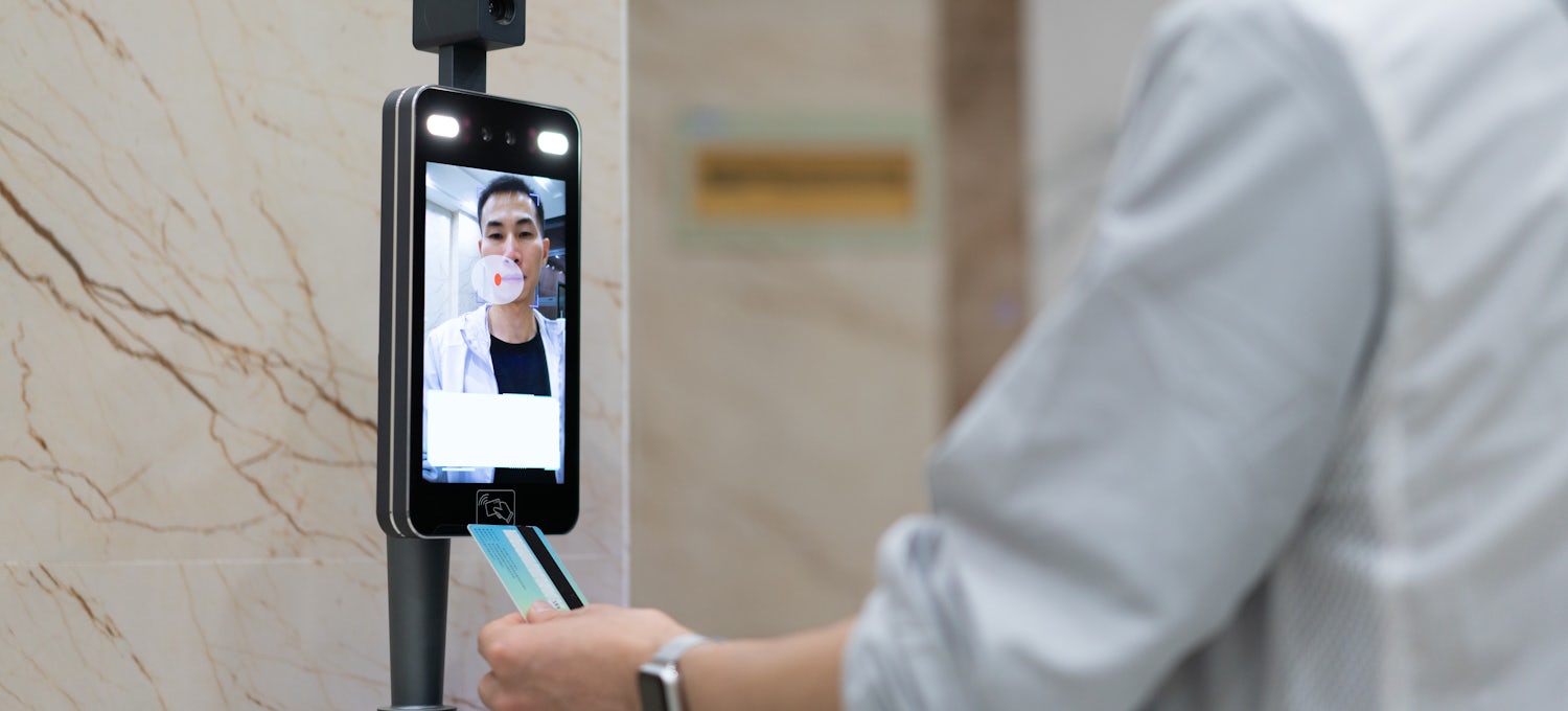 [Featured Image] A man uses facial recognition to get into his office.