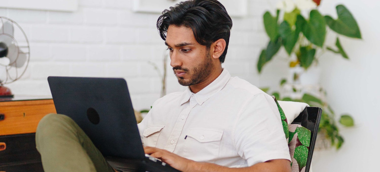 Featured image: A man wearing a white shirt looking at a laptop screen and typing.