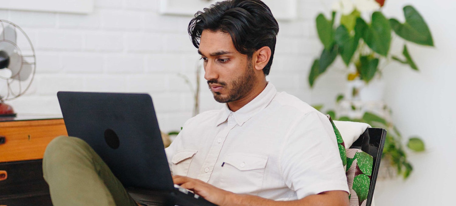 Featured image: A person wearing a white shirt looking at a laptop screen and typing.