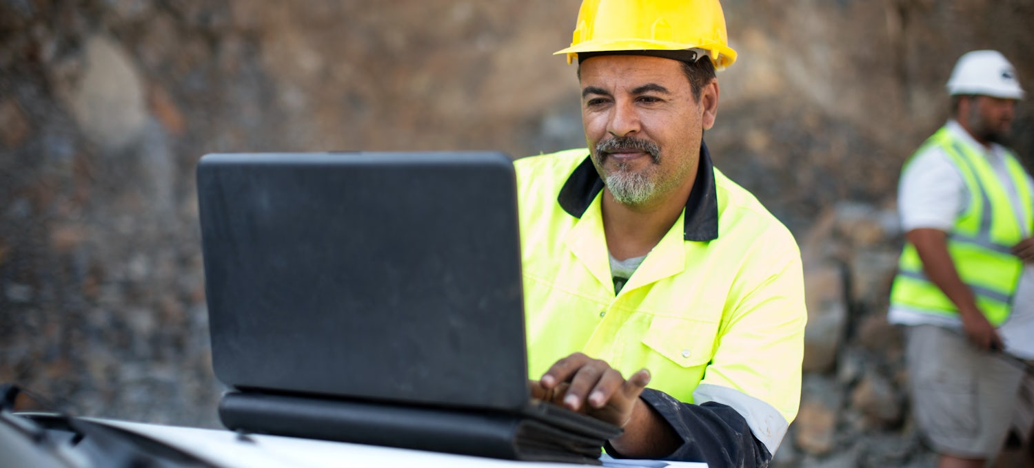[Featured Image] A quarry manager looks at a laptop and uses photogrammetry to make important mining decisions. 