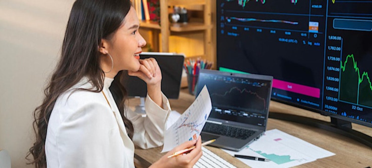 Featured Image: A businessperson is sitting at their desk, looking at a computer monitor that shows different types of correlations related to the stock market.