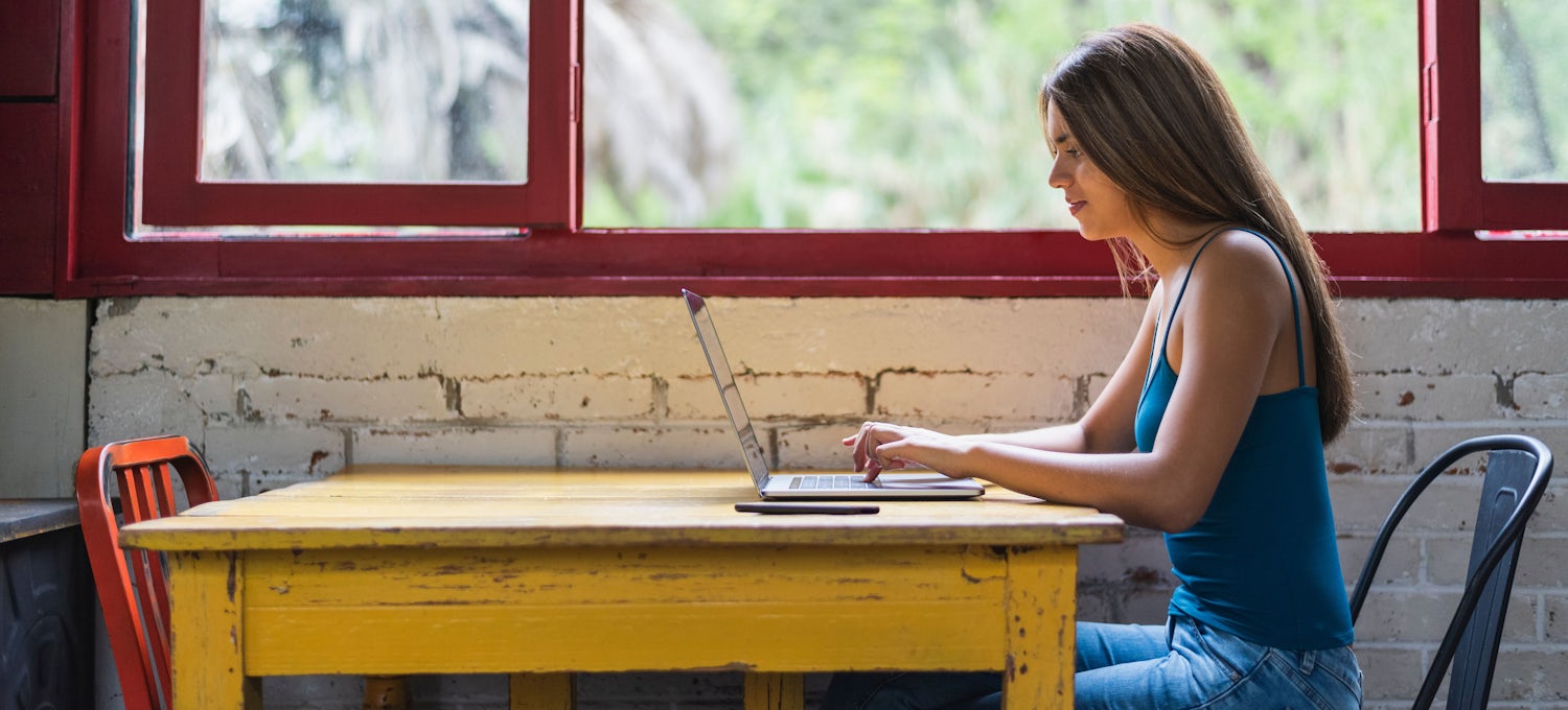 [Featured Image] A woman studies for the SAT exam on her laptop.