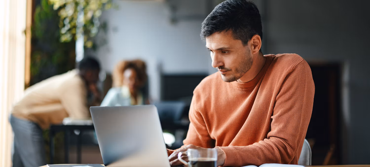 A student is seen typing on his laptop while sitting at his college library.