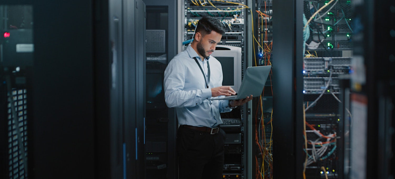[Featured Image} A person working in cybersecurity looks at a laptop with a key AI application.