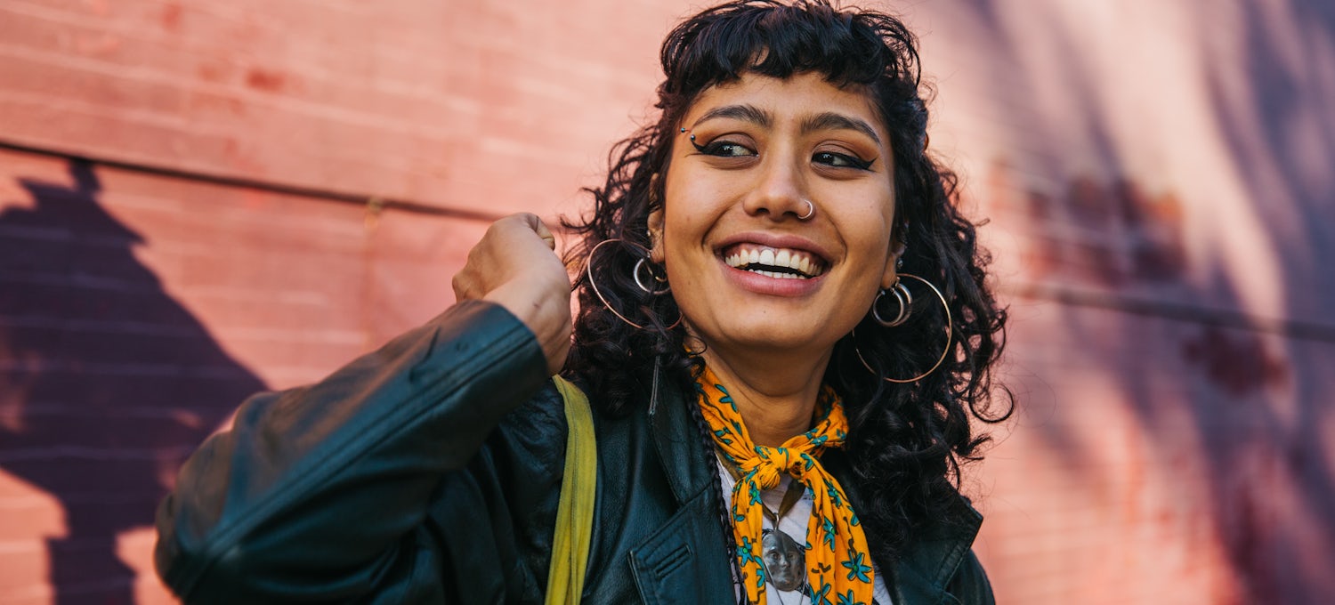 [Featured image] An influencer in a black jacket and orange scarf makes an Instagram Reel to share with their social media audience.