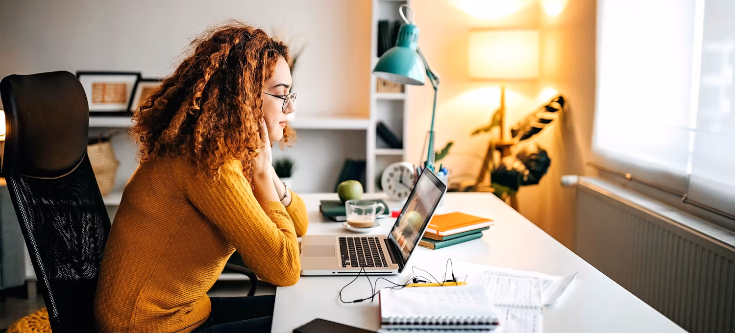 A young prospective female college student looks at a laptop in her home office to determine if she needs a degree to be an accountant.