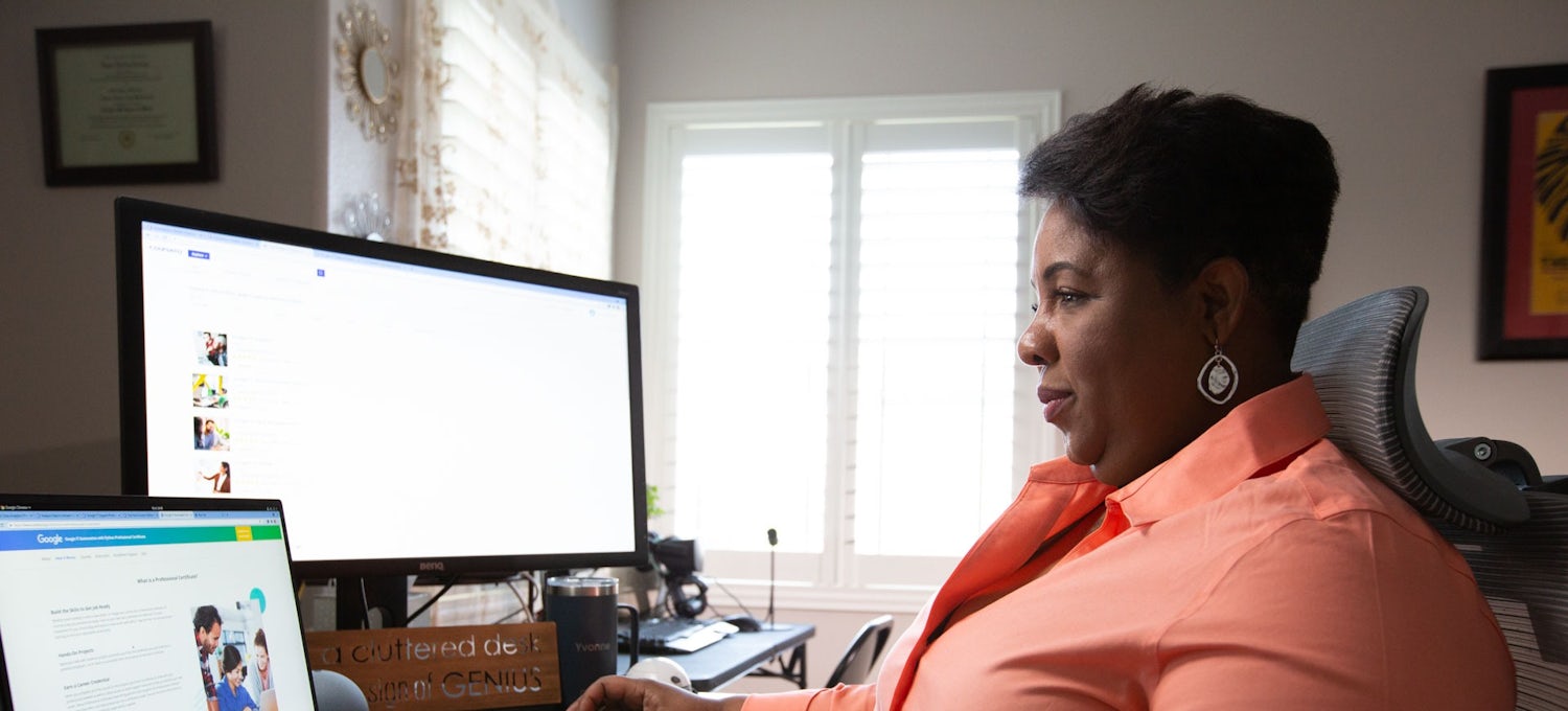 [Featured Image] A remote worker sits in front of a laptop computer and a desktop computer in a home office.