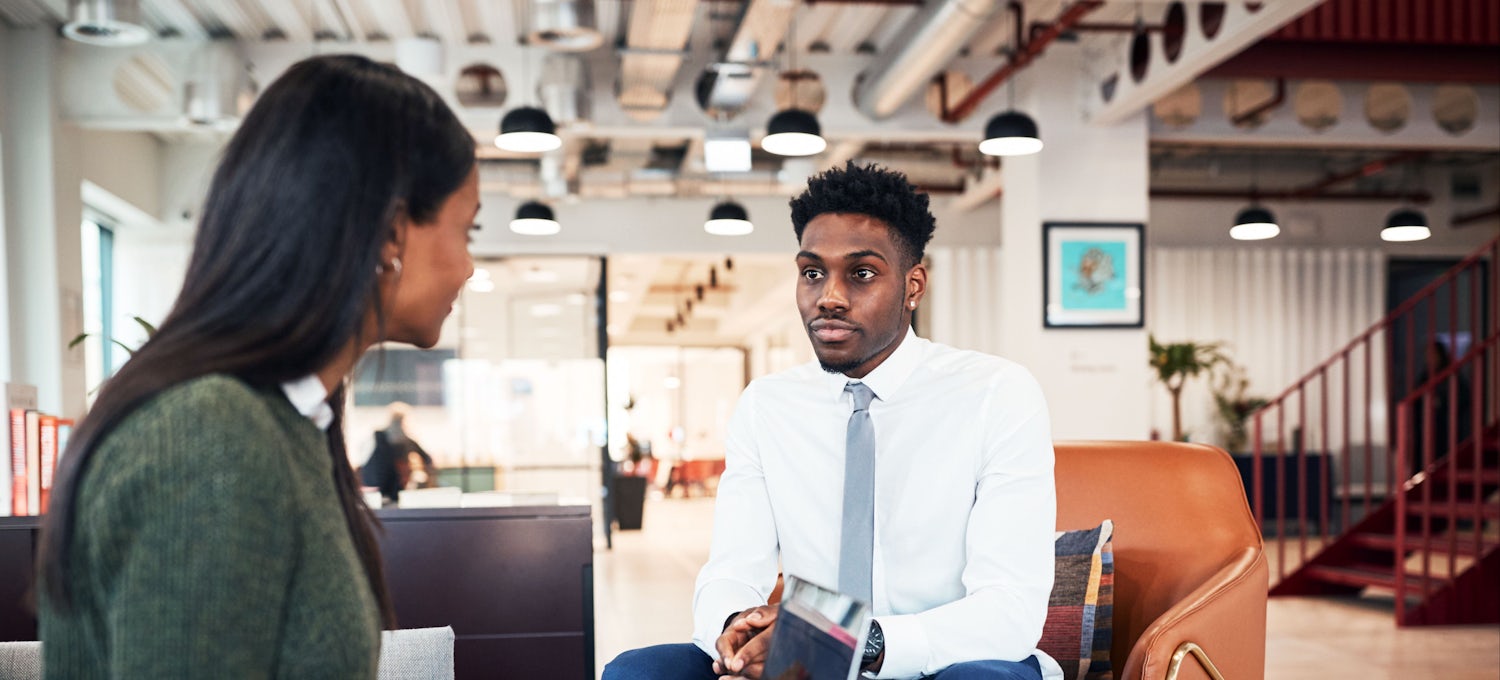 [Featured Image]:  Prospective employee, wearing a white shirt, blue pants, and gray tie, is answering questions about leadership during an interview.