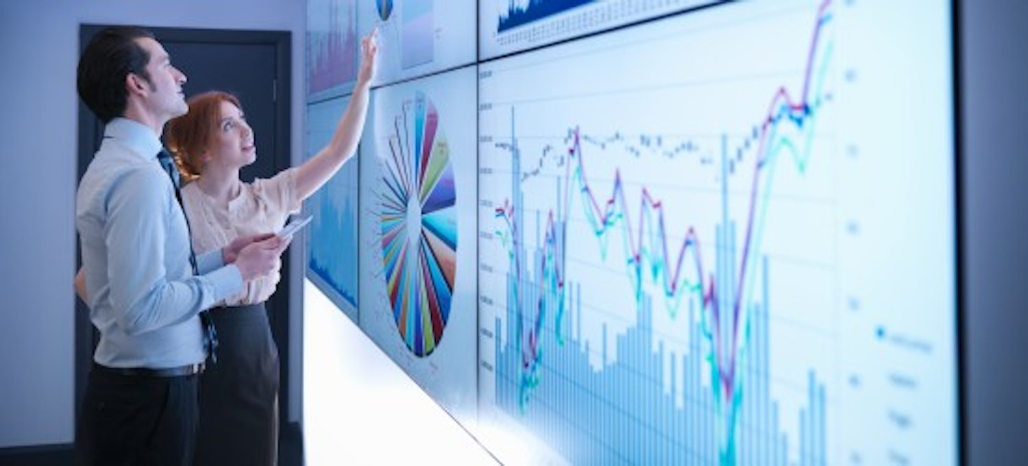 {Featured image} A data scientist explains visualized data to a coworker as they both look at large graphs displayed by a projector on a wall.