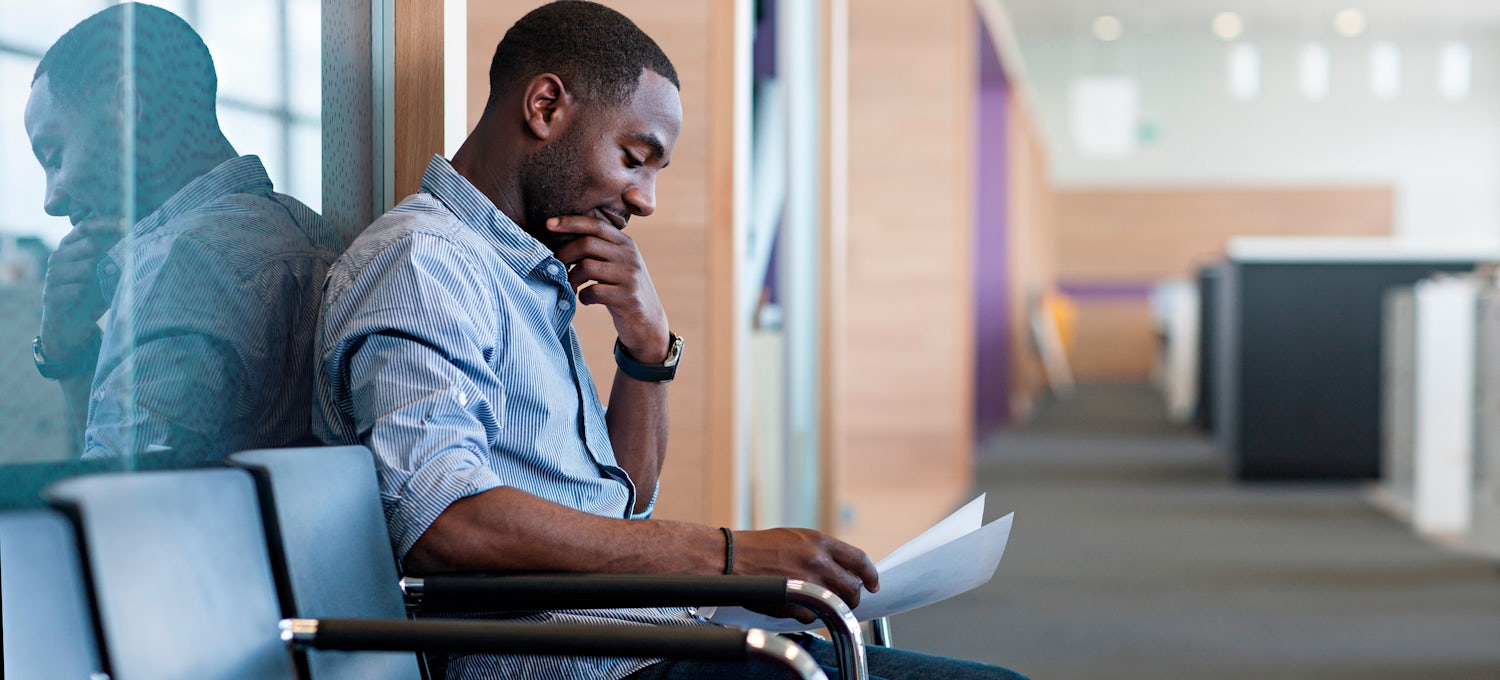 [Featured image] A man sits in a hallway preparing responses for common interview questions.