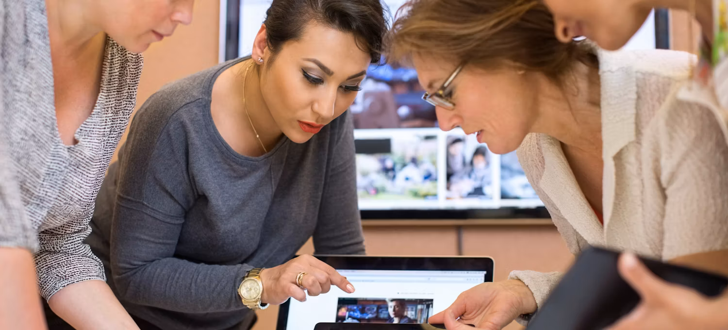 [Featured Image} A group of four tech professionals look at AI generated photos on a laptop and discuss generative AI models.