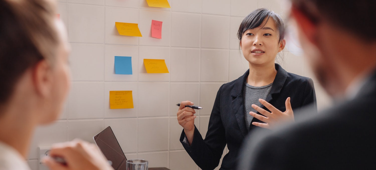 [Featured image] Woman giving a presentation in front of whiteboard
