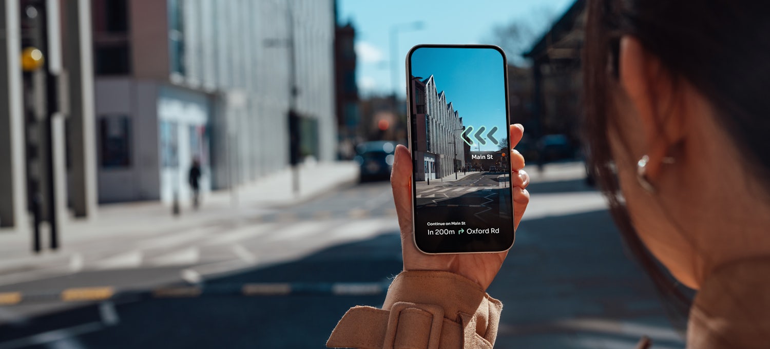 [Featured Image] A woman uses an AR app to find directions in a city.  