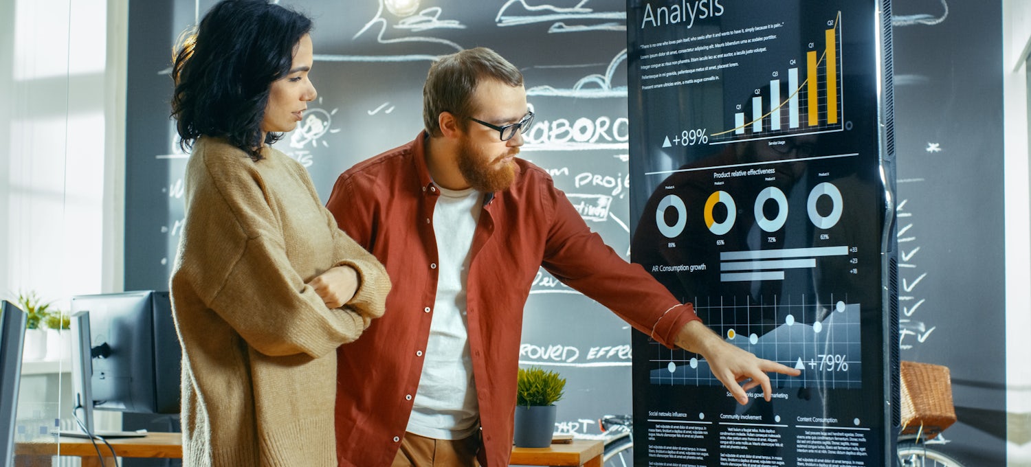 [Featured Image] A man and woman discuss data on a chart.