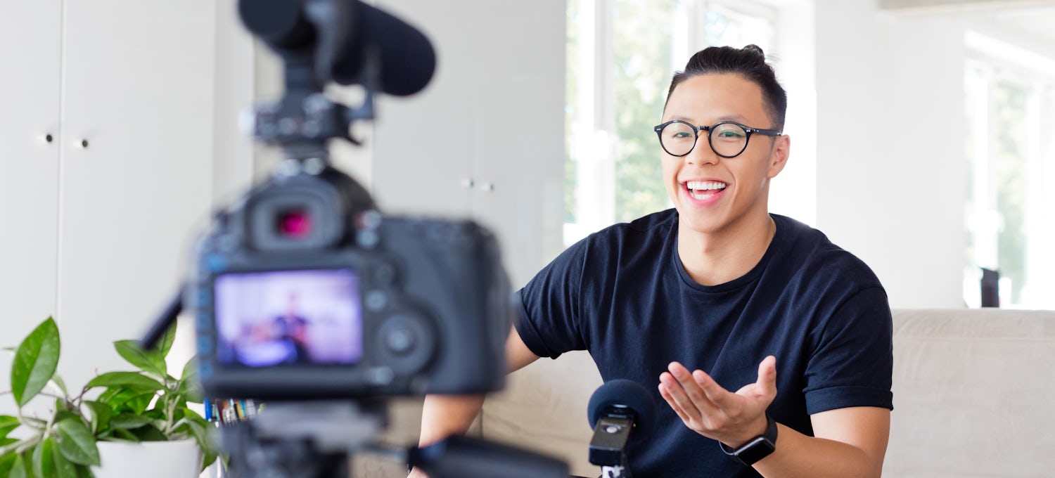 [Featured Image] Man with top bun and round glasses speaks in front of a camera in his living room.