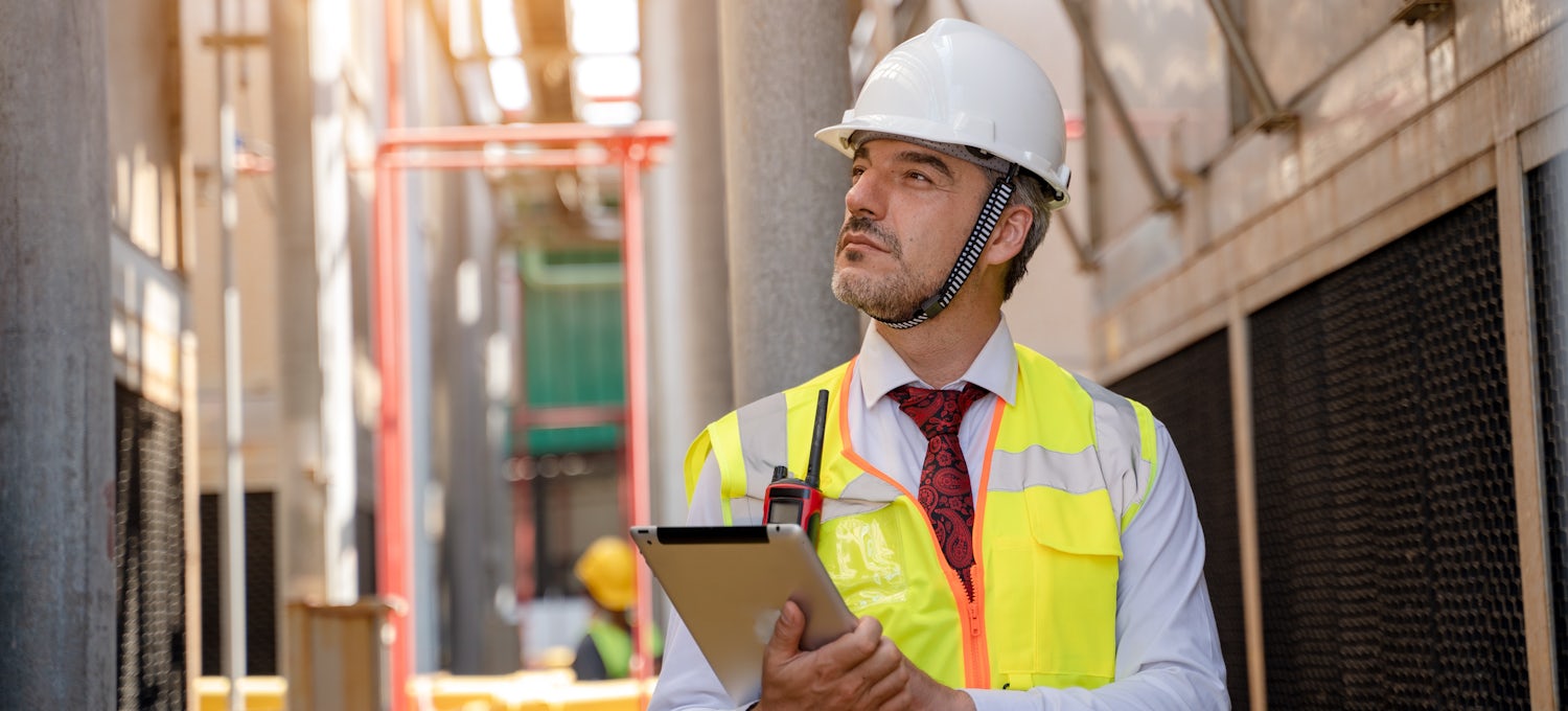 [Featured image] A Man wearing a hard hat inspects a building.

