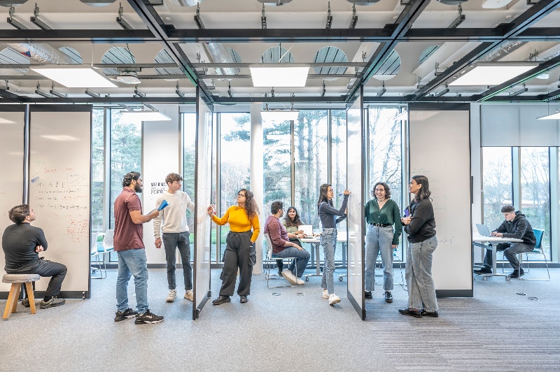 Learner standing at computer with slides behind him