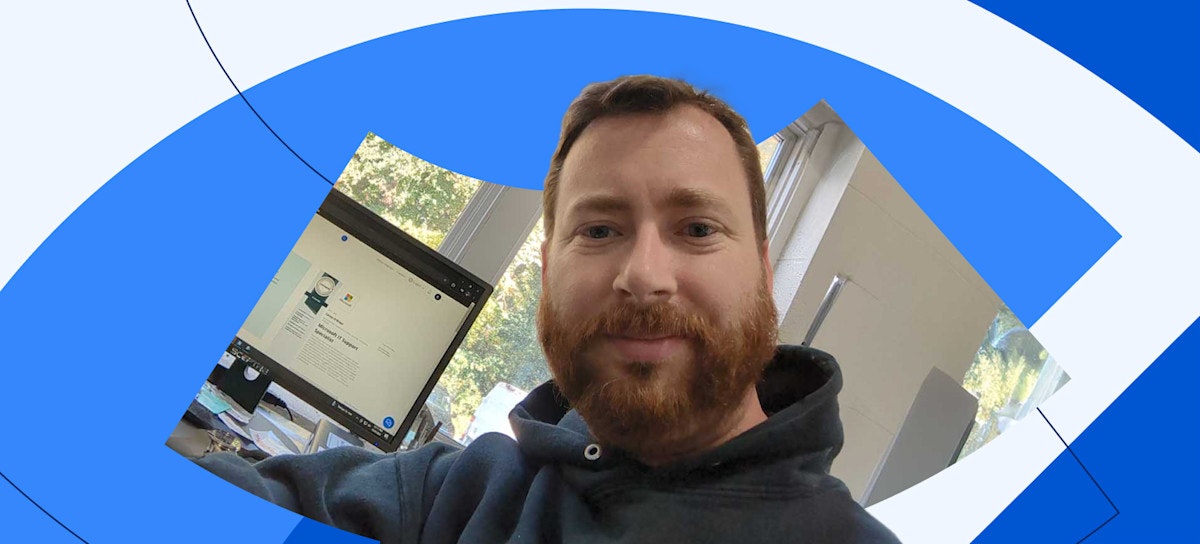 [Featured image] Coursera Plus subscriber Corey O'Brien sits in front of his desktop computer, which displays the certificate he earned after completing the Microsoft IT Support Specialist Professional Certificate.