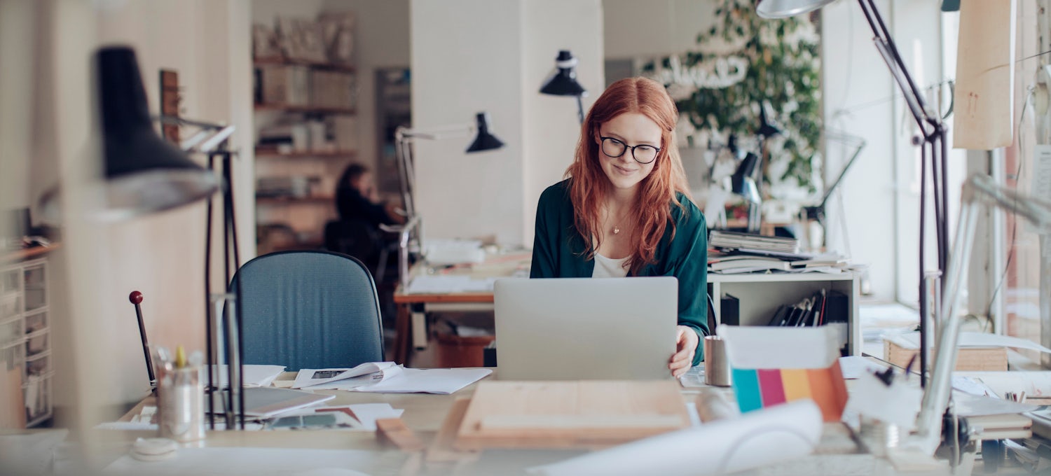 [Featured image] A person with red hair and glasses works on their Microsoft Office certification.