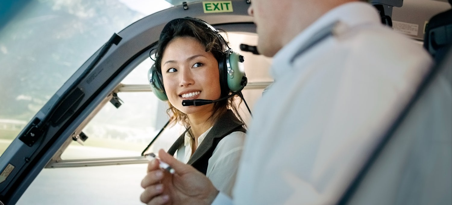 [Featured image] A female trainee pilot listens to her instructor during flight training inside an airplane.