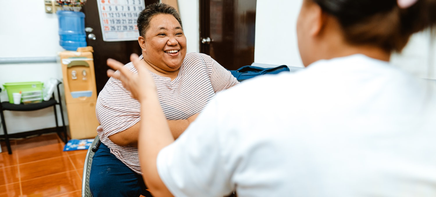 A smiling woman in a wheelchair interviews for a data analyst job with a hiring manager.