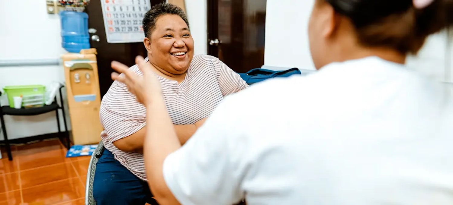 A smiling person in a wheelchair interviews for a data analyst job with a hiring manager.
