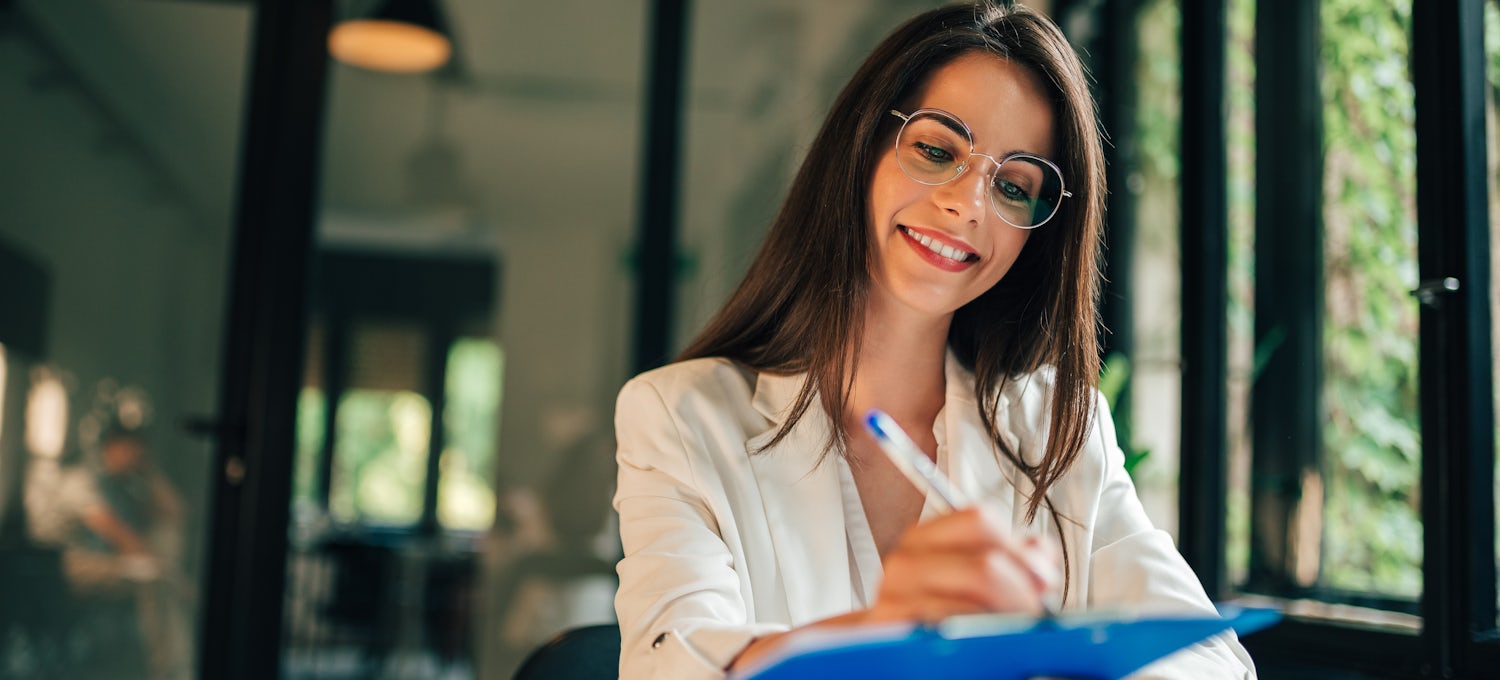 [Featured image] Applicant writes a cover letter on a blue clipboard