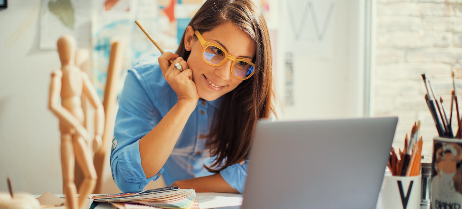 [Featured Image] An information designer works on a project from her desk in her home office. 