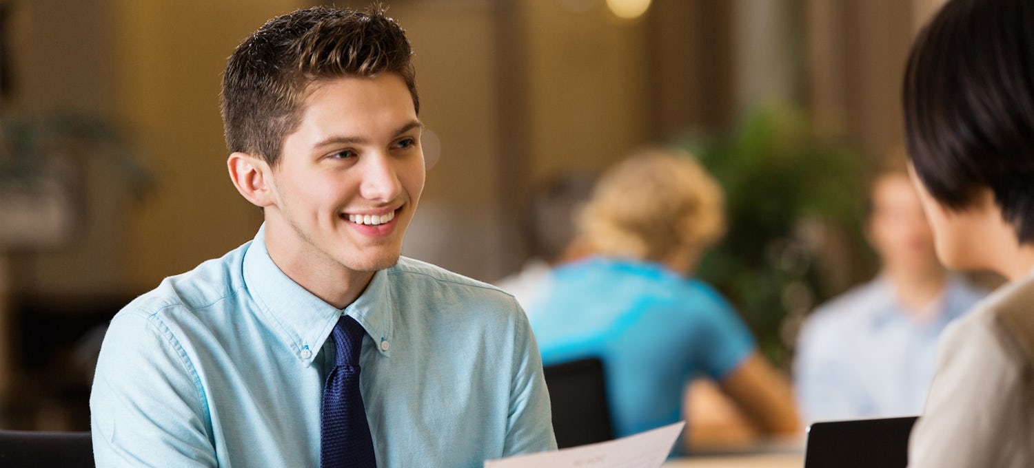 [Imagen destacada] Un hombre con corbata y camisa azul muestra su currículum vítae a un responsable de contratación.