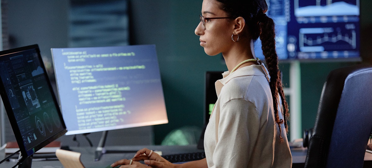 [Featured Image] A professional with software developer skills programs at a computer in an office.