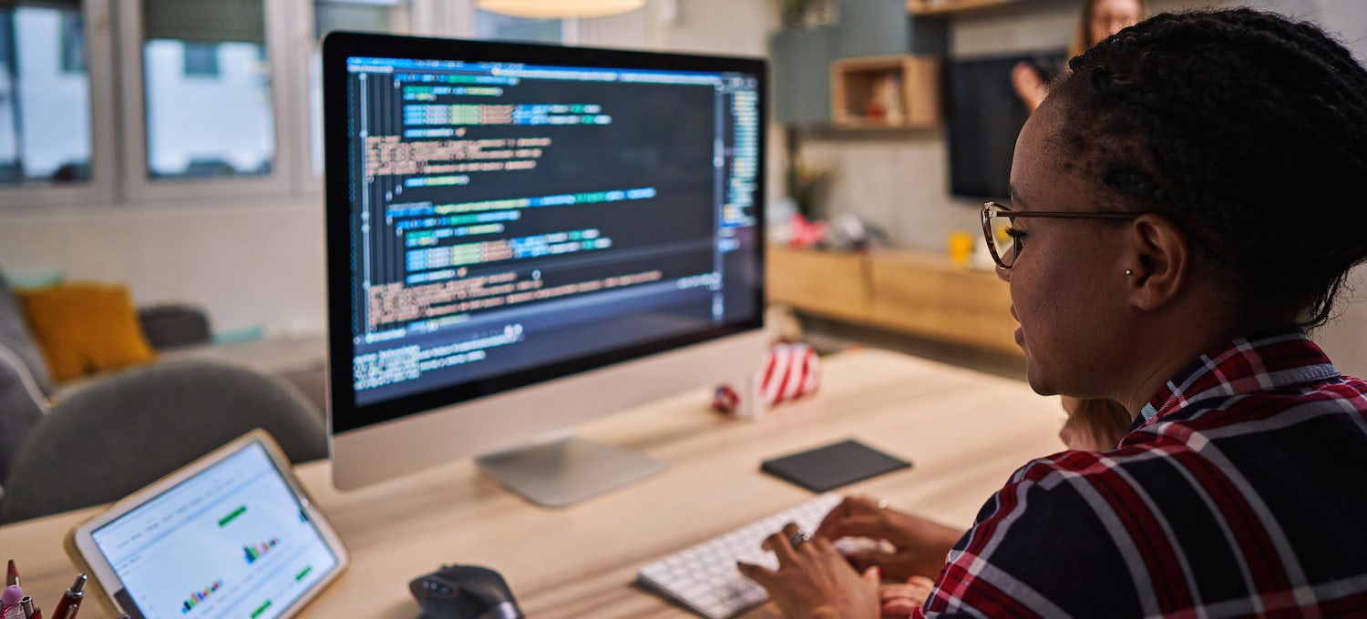 [Featured image] A person wearing glasses and a plaid shirt works on code on a desktop.